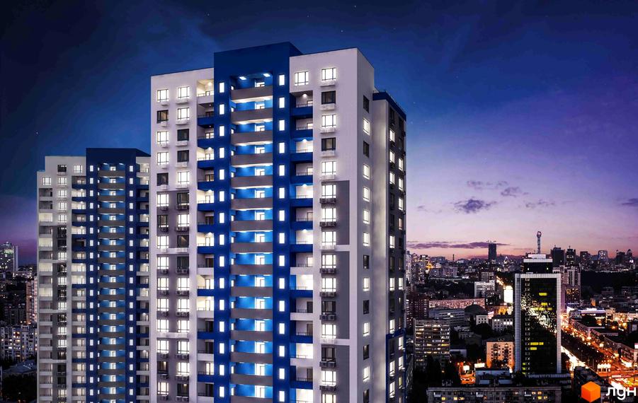 Житловий комплекс Воздухофлотський квартал з яскравою синьо-білою фасадною частиною та численними вікнами, що світяться ввечері. Навколо видно міський пейзаж з іншими будівлями.