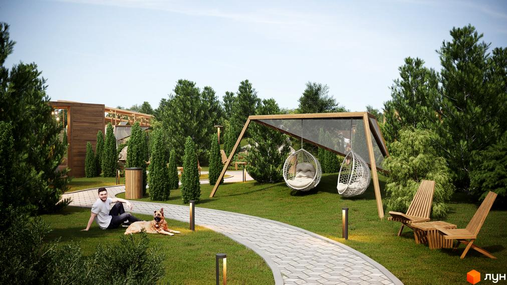 Котеджне містечко Затишний: чоловік з собакою відпочивають на зеленій галявині біля доріжки, на задньому плані гойдалки та дерев'яні шезлонги.
