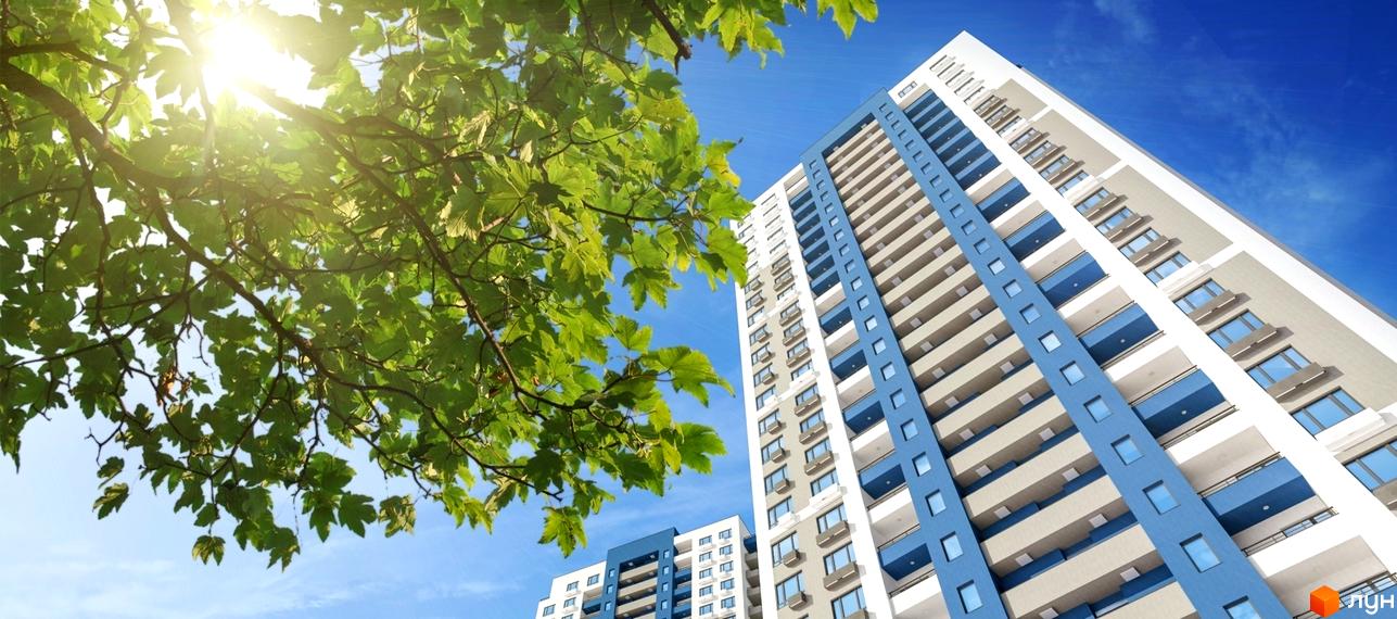 Зовнішній вигляд новобудови ЖК Воздухофлотський квартал з блакитними елементами та балконами на тлі блакитного неба та зелені дерев. Фотографія житлового комплексу.