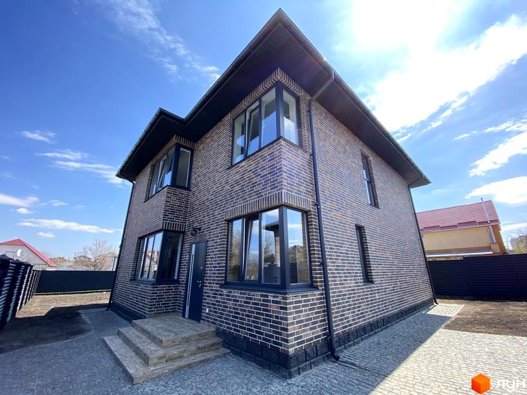 Котеджне містечко КМ Весняний: двоповерховий будинок з цегляним фасадом та прибудинковою територією з бруківки.