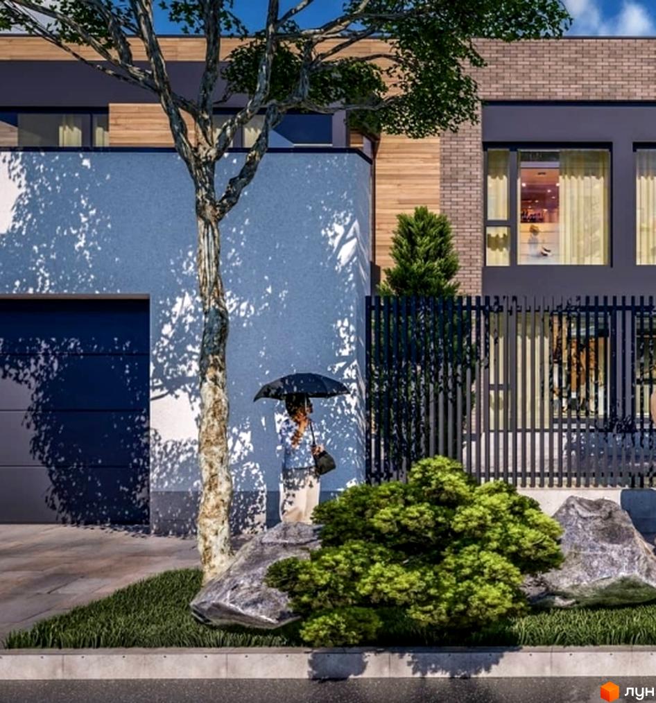 Фасад будинку з комбінацією оздоблення, включаючи дерево та цеглу. На прибудинковій території великі камені, зелені кущі та газон.