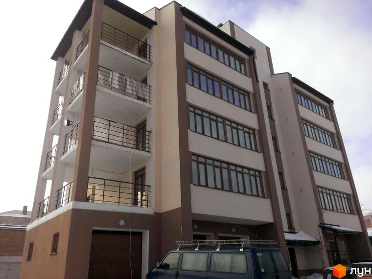 Будинок житлового комплексу на вул. Паневежиська (Пугачова), 2, з балконами та великими вікнами, на тлі хмарного неба. Перед будинком припаркований синій мінівен.