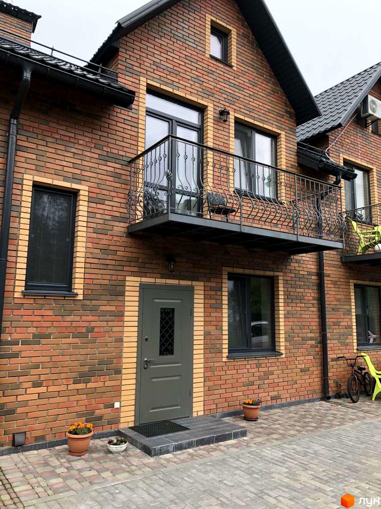 Таунхауси Classic Nova: цегляний будинок з балконом та дверима, прибудинкова територія з квітами та велосипедом.