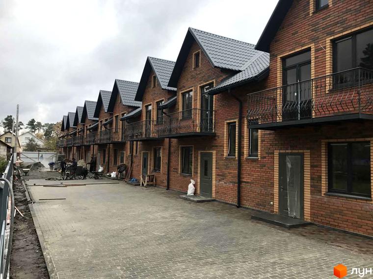 Таунхауси Classic Nova - цегляні будинки з сірим дахом та балконами, що розташовані на вимощеній бруківкою території.