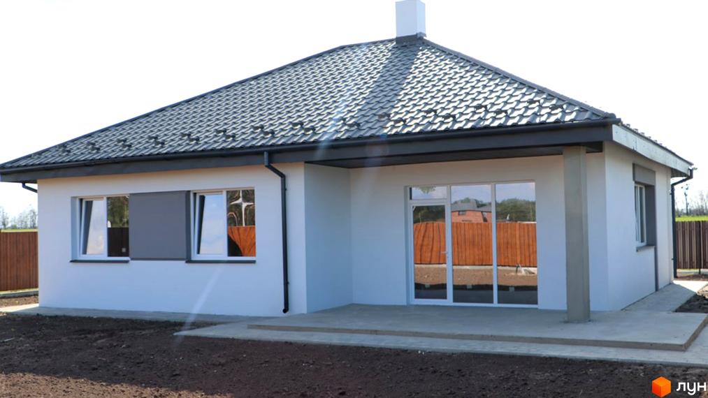 Котеджне містечко КМ Лісне: одноповерховий будинок з сірим дахом, великими вікнами та бетонною терасою. Навколо будинку облаштована прибудинкова територія з огорожею.