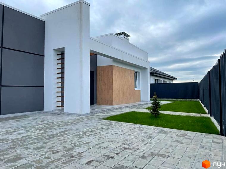 Котеджне містечко КМ Лісне: сучасний будинок з сірими та дерев'яними панелями, вимощеною доріжкою та зеленою галявиною.