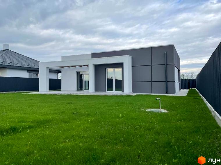 Котеджне містечко КМ Лісне: одноповерховий будинок з сірими та білими фасадами, великими вікнами та зеленою галявиною перед ним.