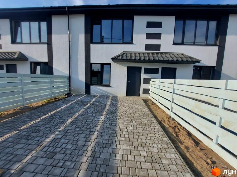 Таунхаус Sanny House з білим фасадом, темними вікнами та сірою бруківкою перед будинком. Огороджена територія з білим парканом.