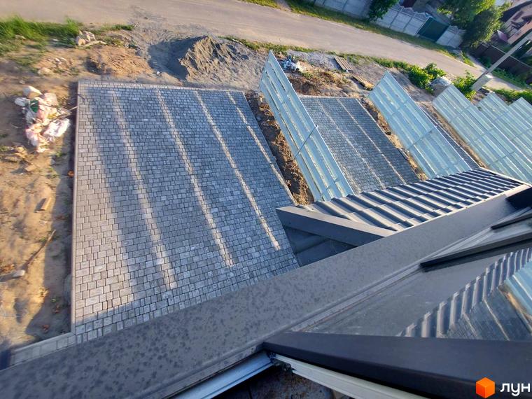 Таунхаус Sanny House з бруківкою та огорожею на прибудинковій території. Зовнішній вигляд будинку з металевим дахом та вікнами.