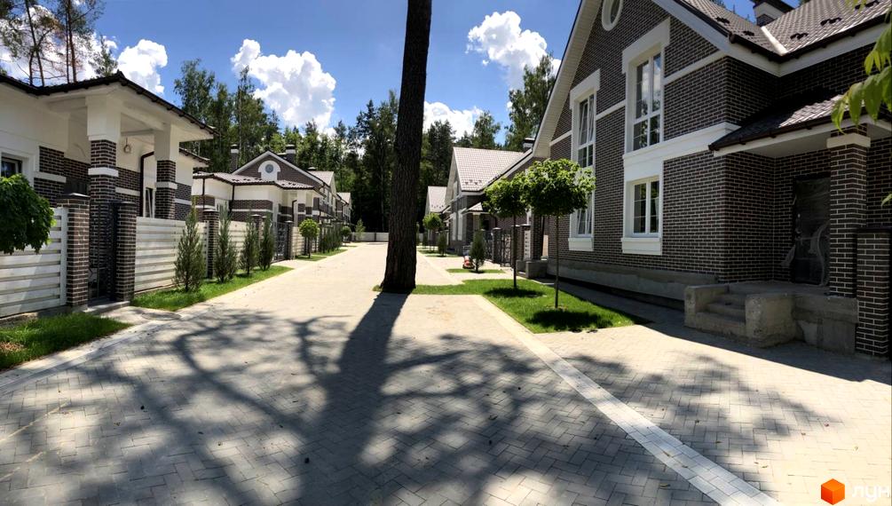 Зображення Котеджного містечка Dream Wood з будинками з цегли та доглянутою прибудинковою територією. Вигляд вулиці з бруківкою та деревами.