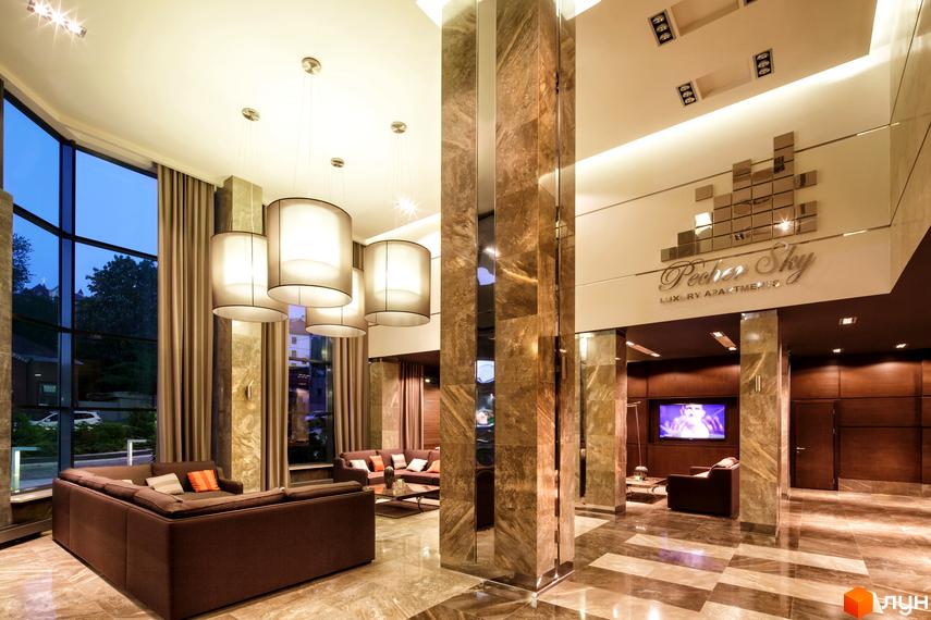 Сучасний вестибюль житлового комплексу PecherSKY з великими вікнами та стильними меблями. Освітлення створює затишну атмосферу.