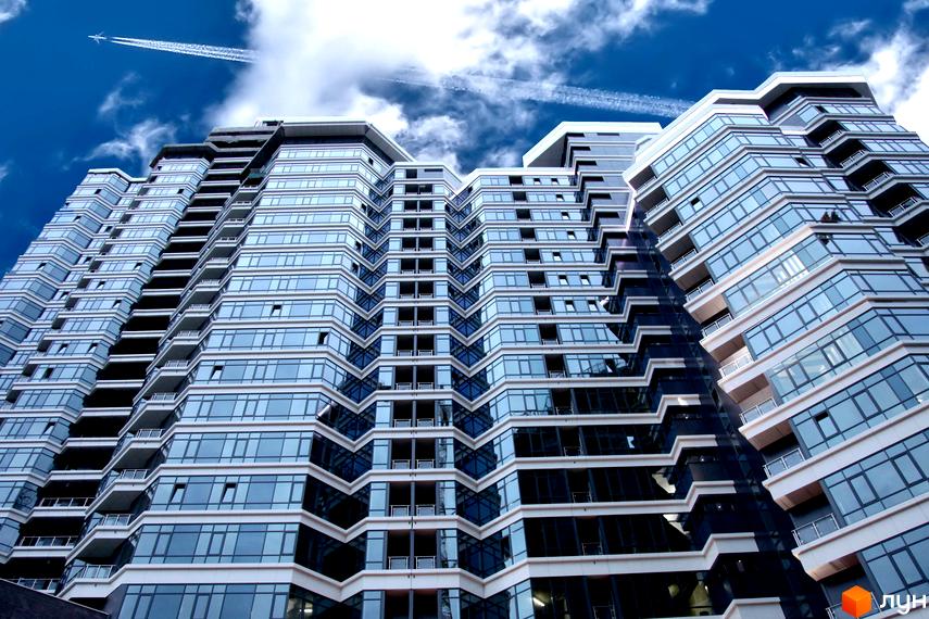 Житловий комплекс PecherSKY з сучасною архітектурою та великими вікнами, оточений зеленими насадженнями.