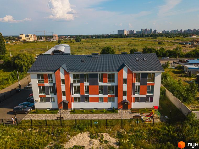 Житловий комплекс Smart Format з фасадом в помаранчево-сірих тонах та прибудинковою територією з дитячим майданчиком.