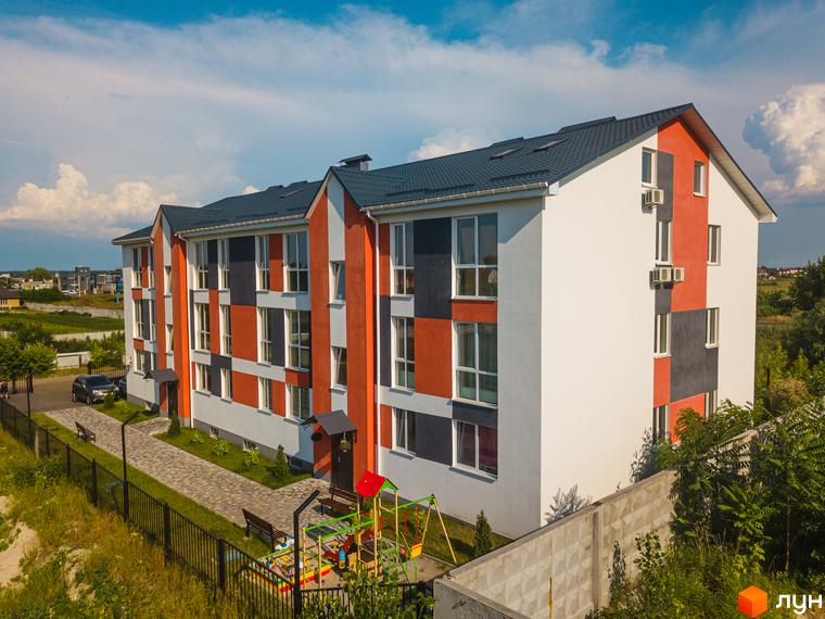 Житловий комплекс Smart Format з фасадом у кольорах червоного, сірого та білого кольорів. Поруч дитячий майданчик та парковка.
