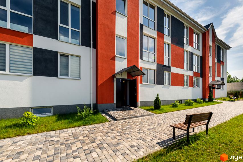 Будинок житлового комплексу Smart Format з фасадом у червоно-чорно-білих кольорах. Поруч вимощена доріжка та зелена трава.