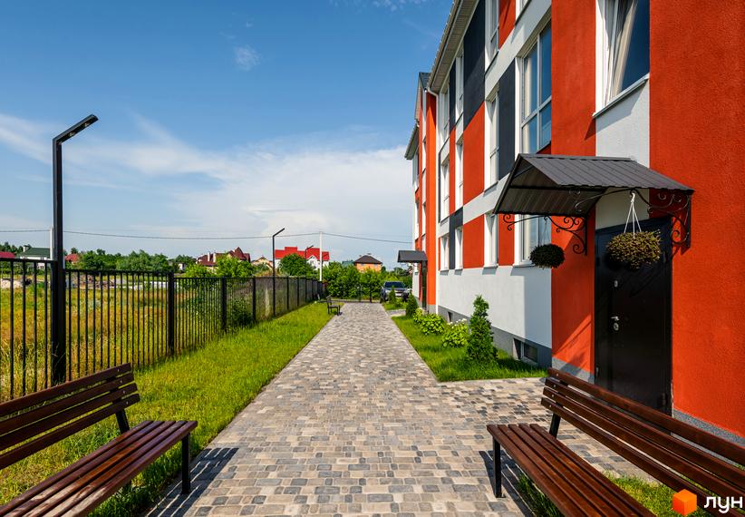 Житловий комплекс Smart Format з яскравим фасадом та доглянутою прибудинковою територією з доріжками та лавками.