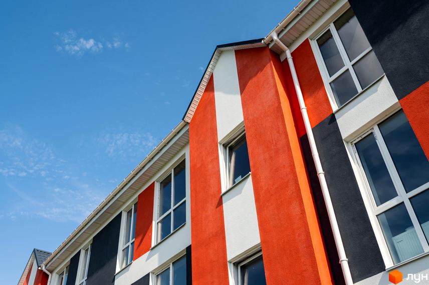 Фасад житлового комплексу Smart Format з яскравим геометричним дизайном у помаранчевих, білих та чорних кольорах. Будинок має великі вікна та білу водостічну систему.