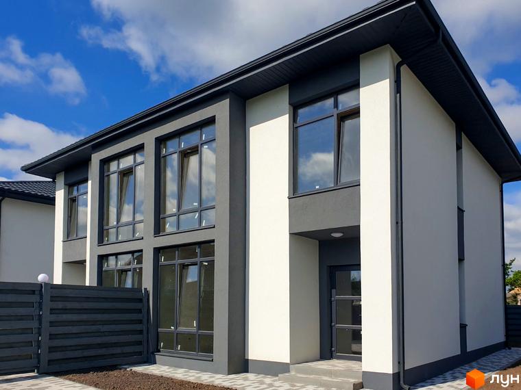 Сучасний двоповерховий будинок з великими вікнами та сірою обробкою фасаду, розташований біля паркану та доріжки.