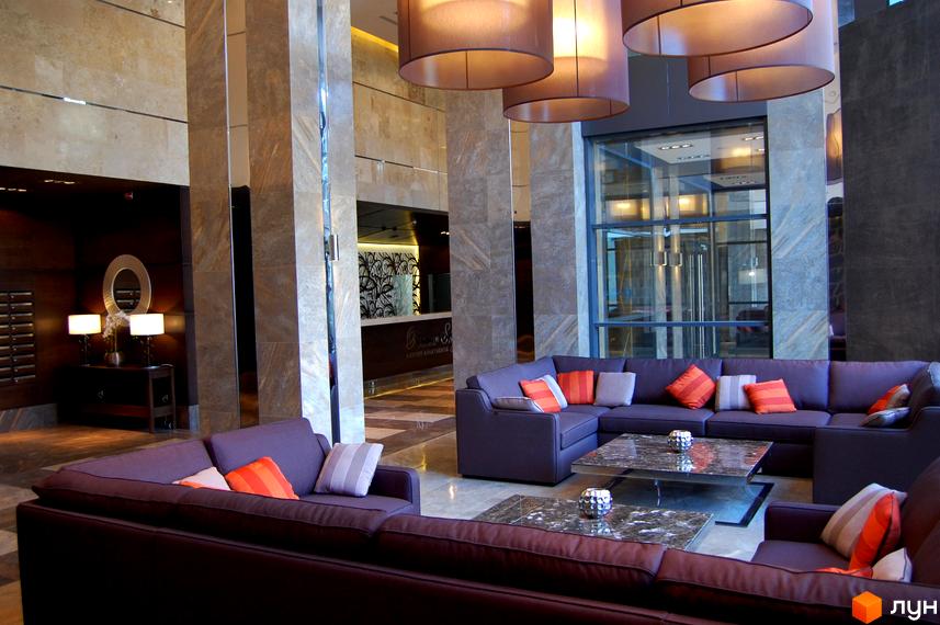 Сучасний інтер'єр лобі житлового комплексу PecherSKY з м'якими диванами та стильними світильниками.