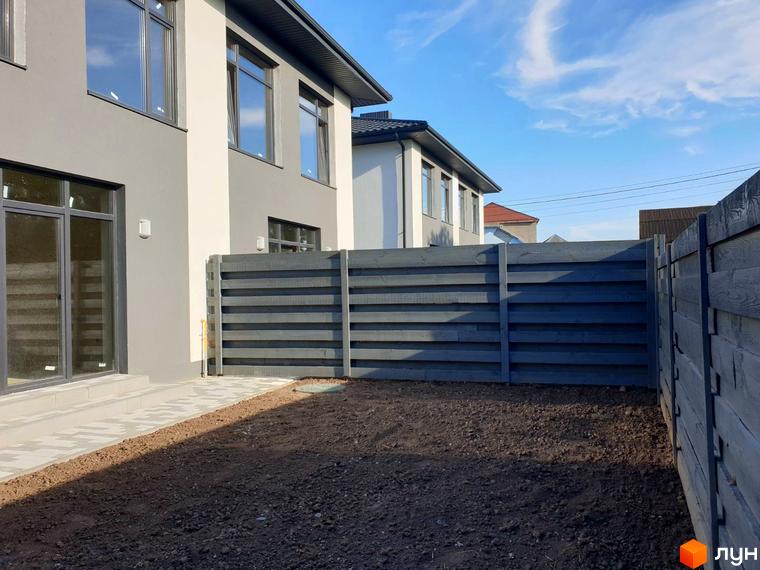 Новобудова на вулиці Шкільна, 2 з сірим парканом та доглянутою прибудинковою територією.