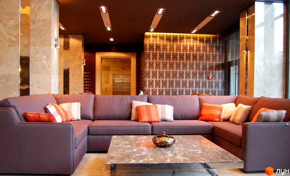 Сучасний інтер'єр холу житлового комплексу PecherSKY з комфортним диваном та стильним столом.