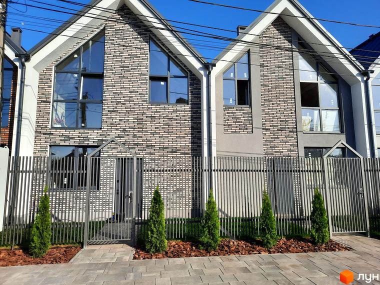 Зображення фасаду та прибудинкової території Котеджного містечка Villa Gatne. Двоповерхові будинки з великими вікнами та металевою огорожею.