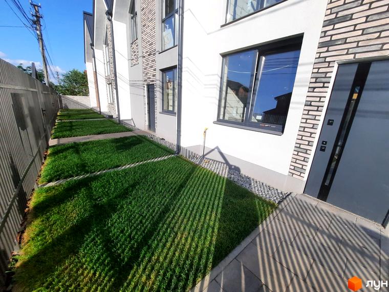 Зовнішній вигляд будинку в Котеджному містечку Villa Gatne. Прибудинкова територія з газоном та тротуарною плиткою.