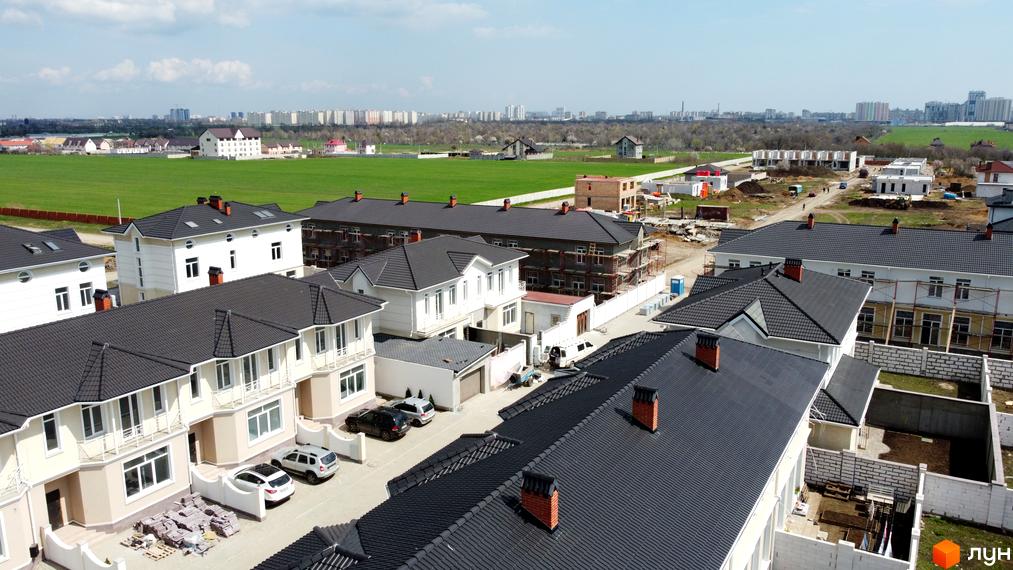 Будинки Котеджного містечка Дайберг зі світлими фасадами та темними дахами. Видно готові та споруджувані котеджі, зелені поля.