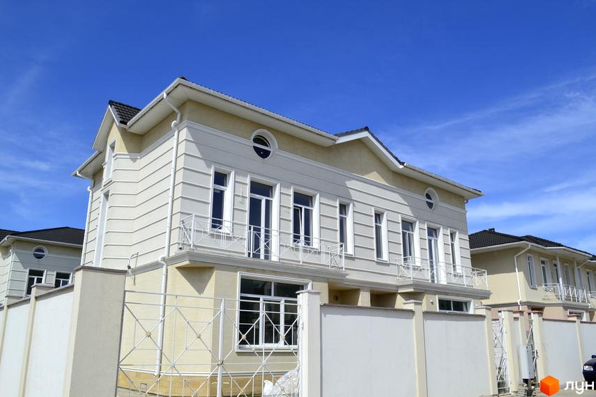 Світлі фасади будинків Котеджного містечка Дайберг з білими вікнами та балконами. Перед будинками видно білий паркан.