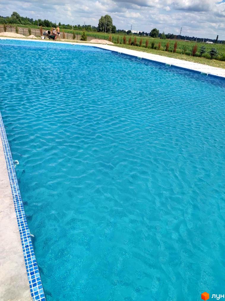 Житловий комплекс Лелека: відкритий басейн з блакитною водою та плиткою по периметру. На задньому плані видно будівельні роботи та зелену зону.