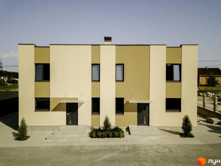 Фасад котеджного містечка КМ My Land: двоповерхові будинки з коричневими та бежевими елементами, великими вікнами та темними дверима. Прибудинкова територія з доріжками з плитки та зеленими насадженнями.