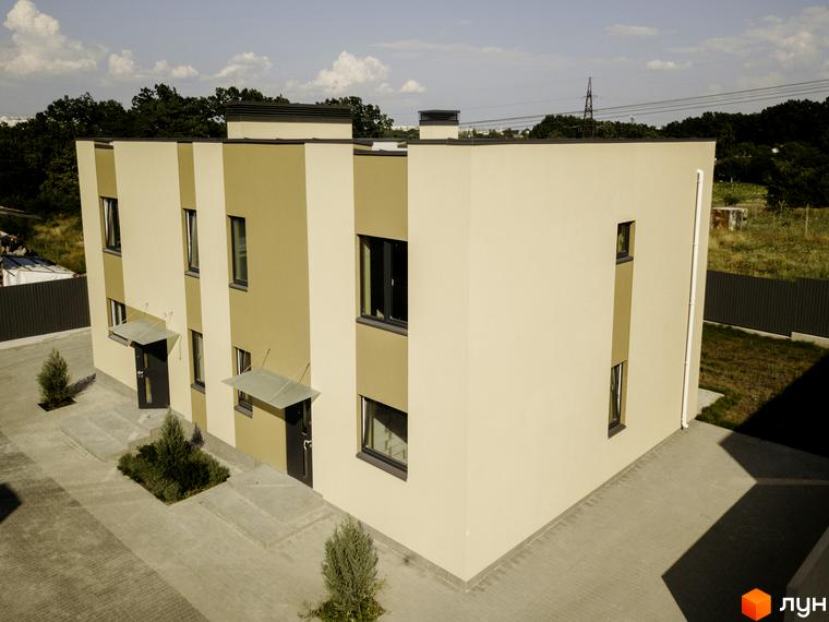 Котеджне містечко КМ My Land - фасади будинків з бежевими та пісочними елементами, вікнами та дверима, прибудинкова територія з бруківкою та зеленими насадженнями.