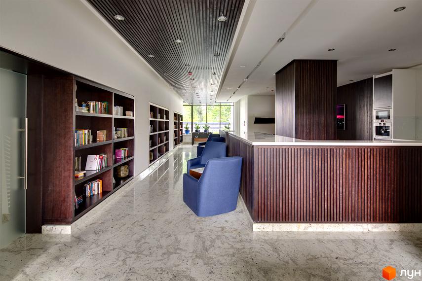 Дизайн інтер'єру ЖК Skyline: простора бібліотека з книжковими шафами та зручні сині крісла. Сучасний простір для відпочинку та читання.