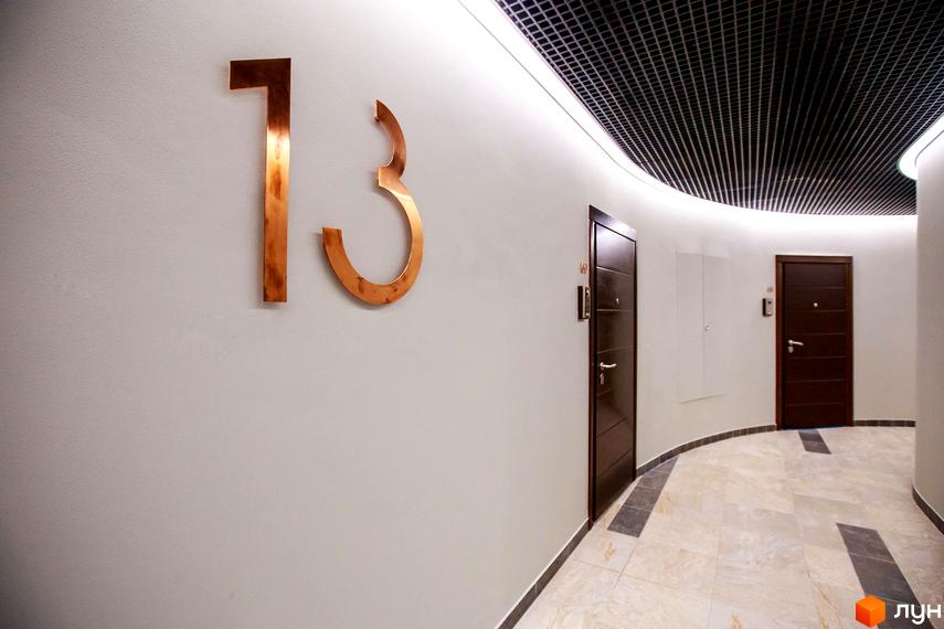 Житловий комплекс Skyline. Номер 13 на стіні коридору з двома дверима та підсвічуванням стелі.
