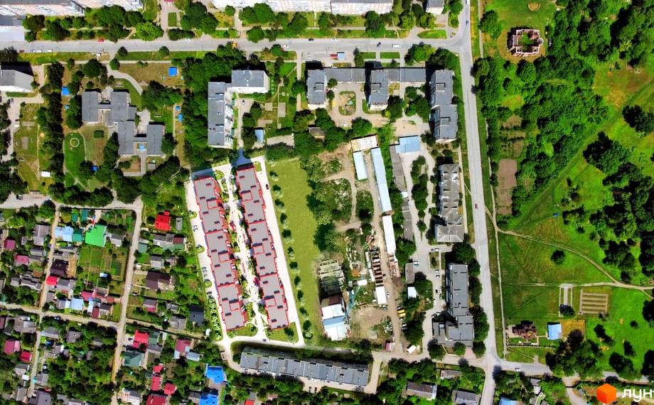 Вид зверху на новобудову ЖК Smart Fort з червоними фасадами та прибудинковою територією з зеленими насадженнями та доріжками.