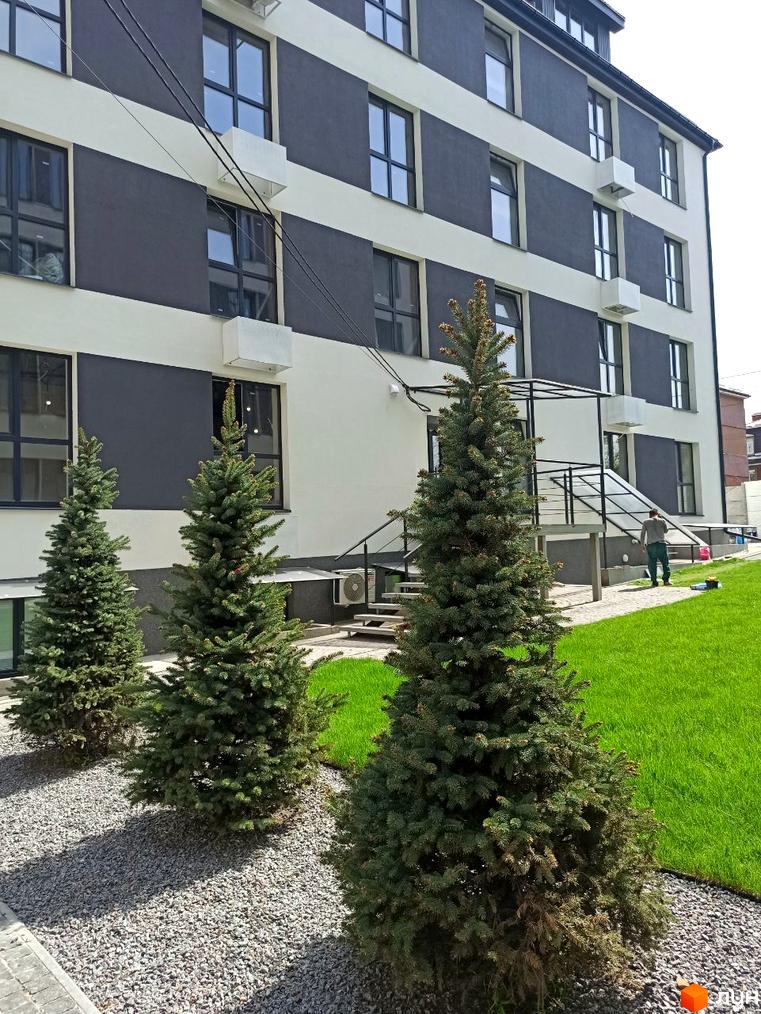 Зовнішній вигляд Клубних будинків „На Генерала Пушкіна“: триповерхова будівля з прибудинковою територією та зеленим газоном.