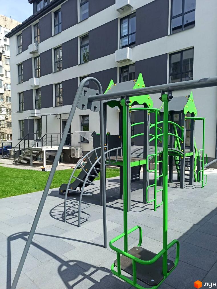 Зображення будинку в Житловому районі „На Генерала Пушкіна“ та дитячого майданчика. Вигляд новобудови з ігровим комплексом для дітей.