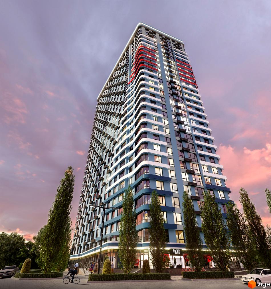 Житловий комплекс Берег Дніпра з блакитним фасадом та червоними акцентами на балконах, на тлі вечірнього неба. Біля будинку дерева та доглянута територія.