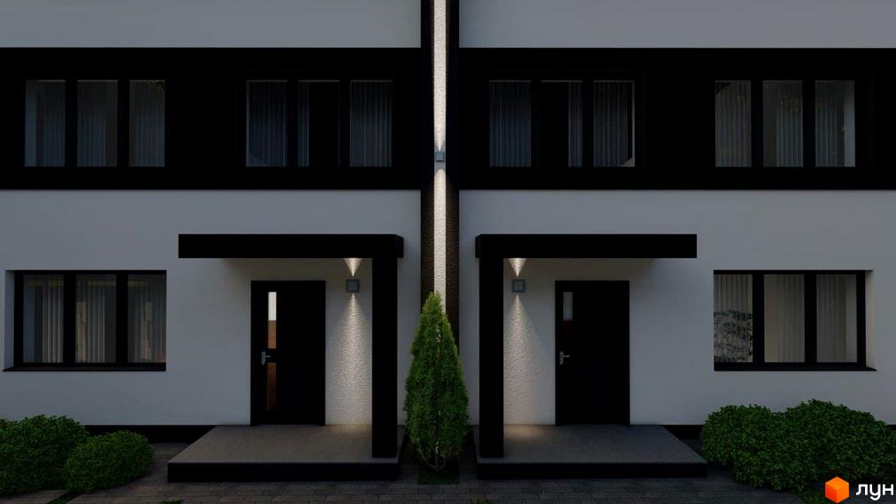 Зовнішній вигляд новобудови на вул. Генерала Гандзюка з чорними віконними рамами та білими стінами, освітленими ліхтарями. Прибудинкова територія з кущами та доріжками.