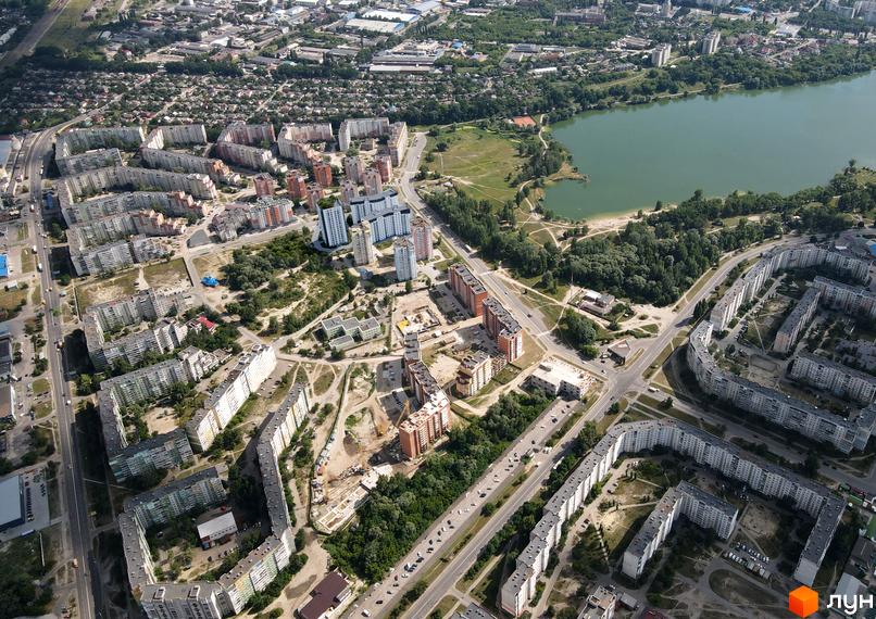 Вид з висоти пташиного польоту на житловий комплекс Iceberg з багатоповерховими будинками сірого та білого кольорів та зеленою прибудинковою територією.