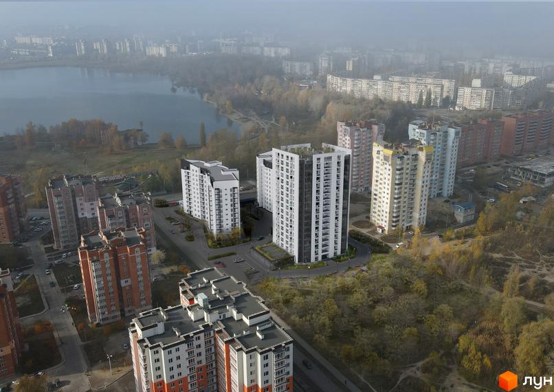 Житловий комплекс Iceberg з білими фасадами та панорамними вікнами, розташований біля водойми та зеленої зони.