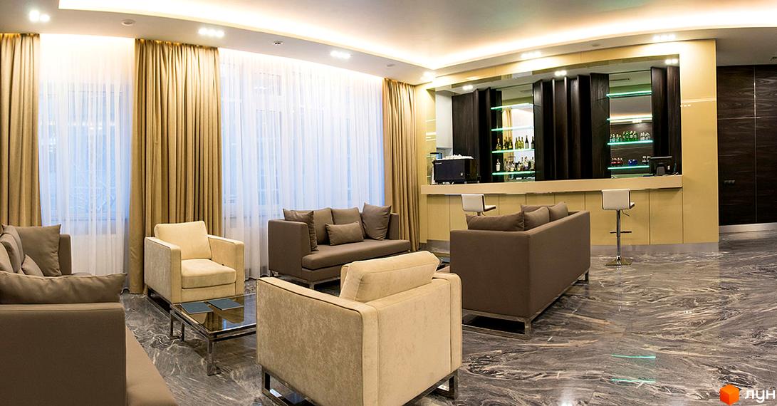 Інтер'єр ЖК Royal Tower: простора вітальня з диванами, баром та великими вікнами. Світле приміщення з мармуровою підлогою, що створює атмосферу комфорту та розкоші.