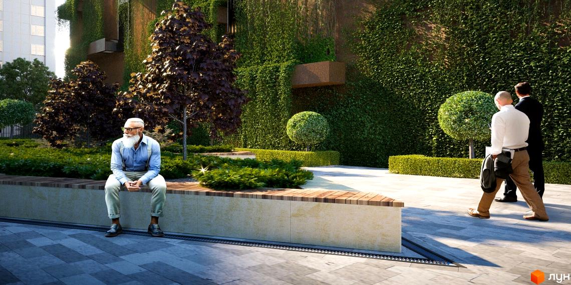 Зелений фасад будівлі з рослинами та ландшафтний дизайн прибудинкової території. На передньому плані чоловік сидить на лавці.