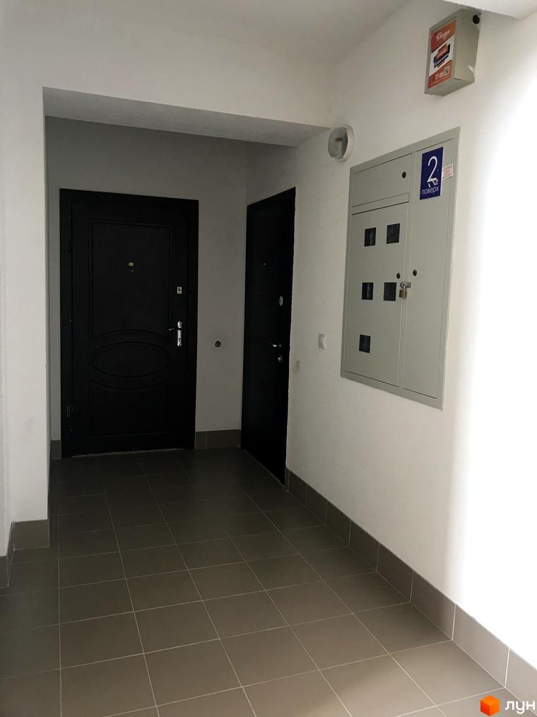 Фотографія поверху в Новобудові Світанковий. Двері в квартири та електрощиток на стіні, плитка на підлозі.