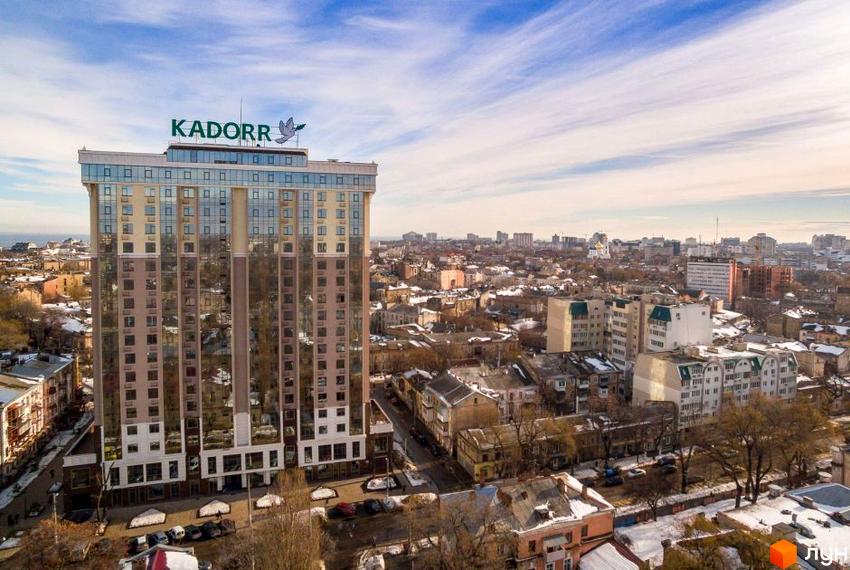 Висотна будівля житлового комплексу KADORR на фоні міської забудови. На даху будівлі розміщено логотип забудовника.