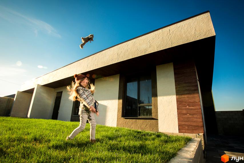 Котеджне містечко La Vida. Будинок з оригінальним дизайном, оздоблений бежевою штукатуркою та дерев'яними панелями, на тлі зеленого газону.