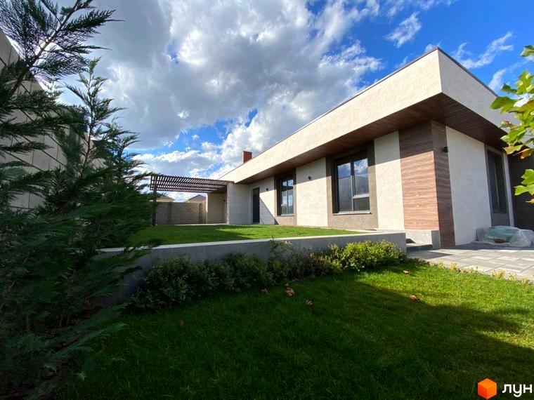 Котеджне містечко La Vida: одноповерховий будинок з великими вікнами та дерев'яними елементами фасаду. Доглянута прибудинкова територія з газоном та зеленими насадженнями.