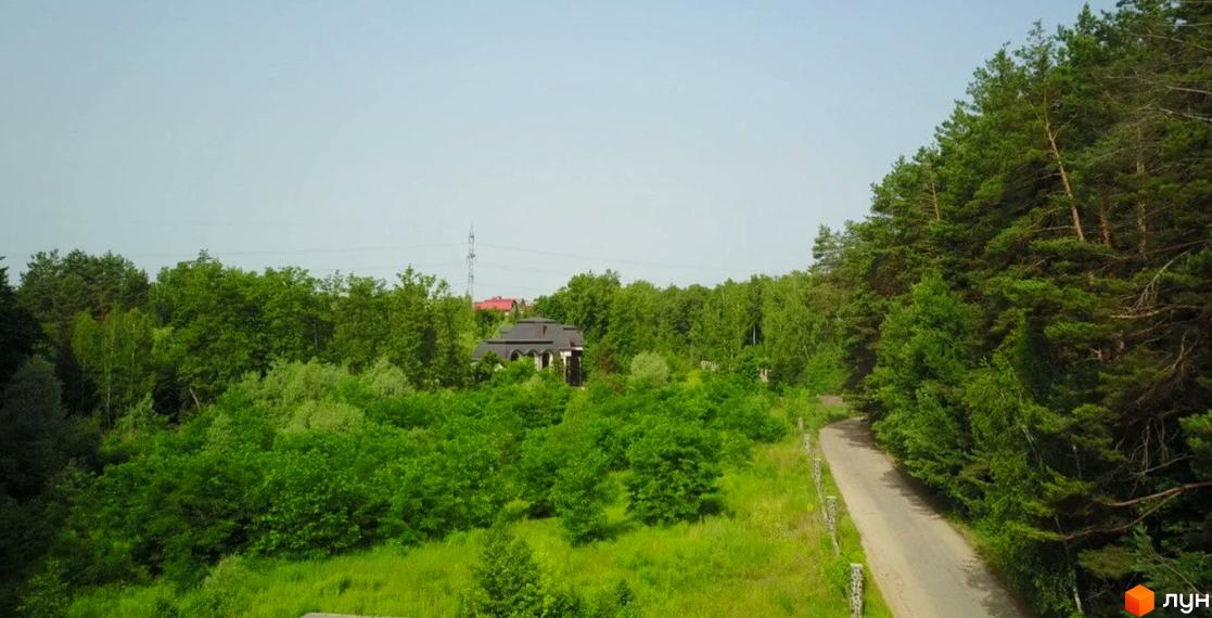 Котеджне містечко LAKESIDE OASIS із зеленими деревами та дорогою, що веде до будинку.