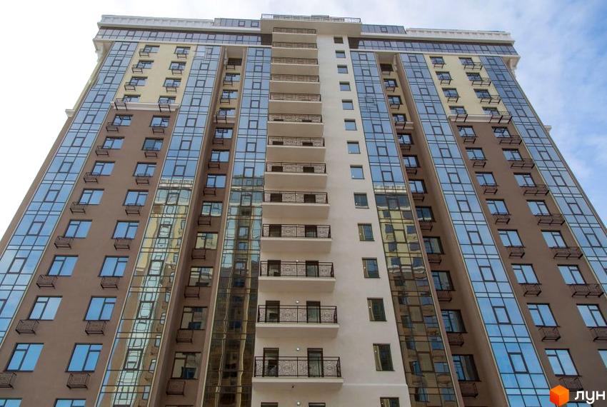 Висотна будівля ЖК Шістнадцята Перлина з великою кількістю скляних вікон. Фасад будинку виконаний у світлих тонах, з балконами та декоративними елементами.
