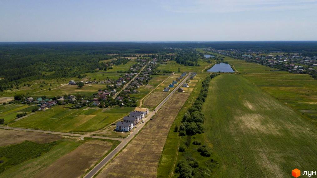 Житловий комплекс Лелека: вид з повітря на багатоповерхові будинки та зелені поля навколо. Комплекс розташований біля озера та лісу.